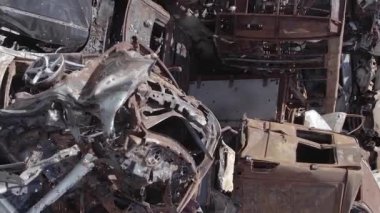 This stock vertical video shows a dump of shot and burned cars in Irpin, Bucha district , grey, flat video