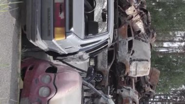 This stock vertical video shows a dump of shot and burned cars in Irpin, Bucha district , grey, flat video