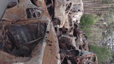 This stock vertical video shows a dump of shot and burned cars in Irpin, Bucha district , grey, flat video