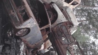 This stock vertical video shows a dump of shot and burned cars in Irpin, Bucha district , grey, flat video