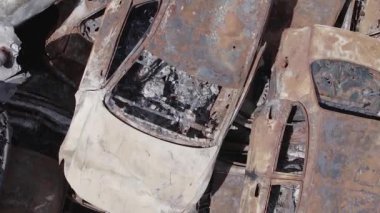 This stock vertical video shows a dump of shot and burned cars in Irpin, Bucha district , grey, flat video