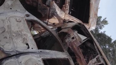 This stock vertical video shows a dump of shot and burned cars in Irpin, Bucha district , grey, flat video