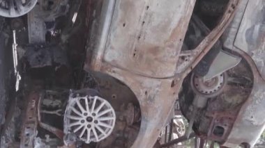 This stock vertical video shows a dump of shot and burned cars in Irpin, Bucha district , grey, flat video