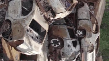 This stock vertical video shows a dump of shot and burned cars in Irpin, Bucha district , grey, flat video