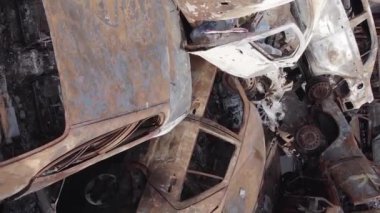 This stock vertical video shows a dump of shot and burned cars in Irpin, Bucha district , grey, flat video