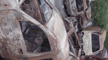 This stock vertical video shows a dump of shot and burned cars in Irpin, Bucha district , grey, flat video
