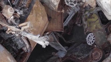 This stock vertical video shows a dump of shot and burned cars in Irpin, Bucha district , grey, flat video