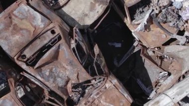 This stock vertical video shows a dump of shot and burned cars in Irpin, Bucha district , grey, flat video
