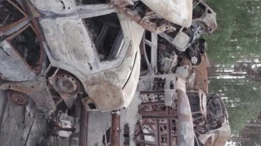This stock vertical video shows a dump of shot and burned cars in Irpin, Bucha district , grey, flat video