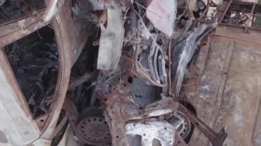 This stock vertical video shows a dump of shot and burned cars in Irpin, Bucha district , grey, flat video