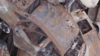 This stock vertical video shows a dump of shot and burned cars in Irpin, Bucha district , grey, flat video