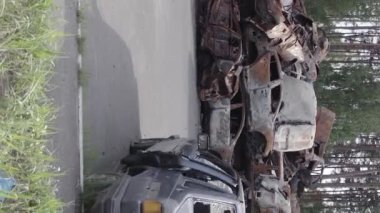 This stock vertical video shows a dump of shot and burned cars in Irpin, Bucha district , grey, flat video