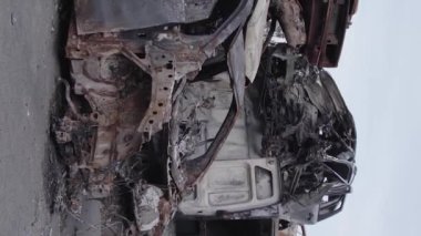 This stock vertical video shows a dump of shot and burned cars in Irpin, Bucha district , grey, flat video