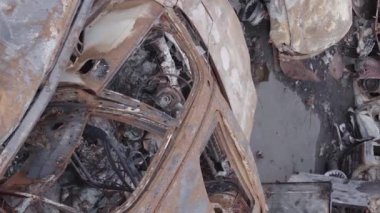 This stock vertical video shows a dump of shot and burned cars in Irpin, Bucha district , grey, flat video