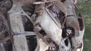 This stock vertical video shows a dump of shot and burned cars in Irpin, Bucha district , grey, flat video