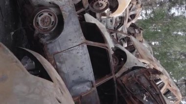 This stock vertical video shows a dump of shot and burned cars in Irpin, Bucha district , grey, flat video