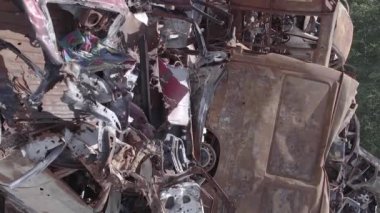 This stock vertical video shows a dump of shot and burned cars in Irpin, Bucha district , grey, flat video