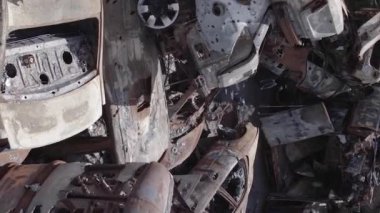 This stock vertical video shows a dump of shot and burned cars in Irpin, Bucha district , grey, flat video