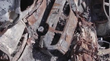 This stock vertical video shows a dump of shot and burned cars in Irpin, Bucha district , grey, flat video