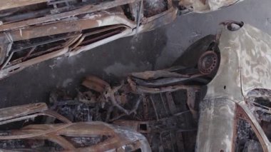 This stock vertical video shows a dump of shot and burned cars in Irpin, Bucha district , grey, flat video