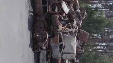 This stock vertical video shows a dump of shot and burned cars in Irpin, Bucha district , grey, flat video