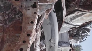 This stock vertical video shows a dump of shot and burned cars in Irpin, Bucha district , grey, flat video