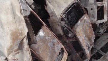 This stock vertical video shows a dump of shot and burned cars in Irpin, Bucha district , grey, flat video