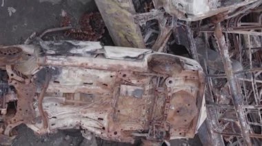 This stock vertical video shows a dump of shot and burned cars in Irpin, Bucha district , grey, flat video