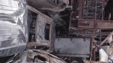 This stock vertical video shows a dump of shot and burned cars in Irpin, Bucha district , grey, flat video