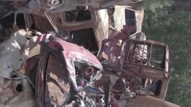This stock vertical video shows a dump of shot and burned cars in Irpin, Bucha district , grey, flat video