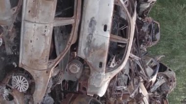 This stock vertical video shows a dump of shot and burned cars in Irpin, Bucha district , grey, flat video