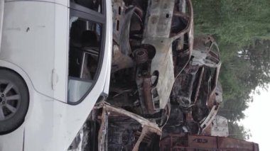 This stock vertical video shows a dump of shot and burned cars in Irpin, Bucha district , grey, flat video