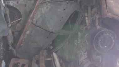 This stock vertical video shows a dump of shot and burned cars in Irpin, Bucha district , grey, flat video