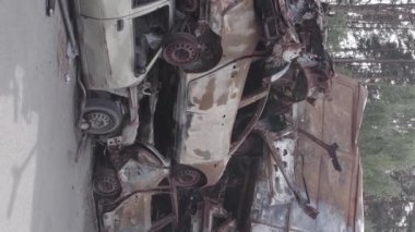 This stock vertical video shows a dump of shot and burned cars in Irpin, Bucha district , grey, flat video