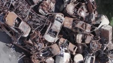 This stock vertical video shows a dump of shot and burned cars in Irpin, Bucha district , grey, flat video