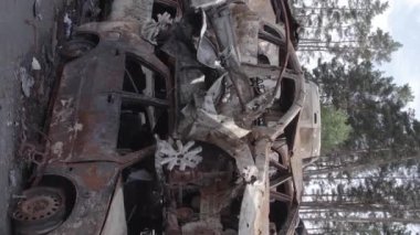 This stock vertical video shows a dump of shot and burned cars in Irpin, Bucha district , grey, flat video