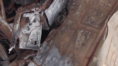 This stock vertical video shows a dump of shot and burned cars in Irpin, Bucha district , grey, flat video