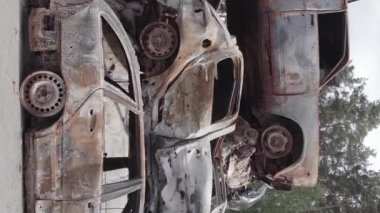 This stock vertical video shows a dump of shot and burned cars in Irpin, Bucha district , grey, flat video