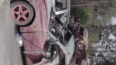 This stock vertical video shows a dump of shot and burned cars in Irpin, Bucha district , grey, flat video