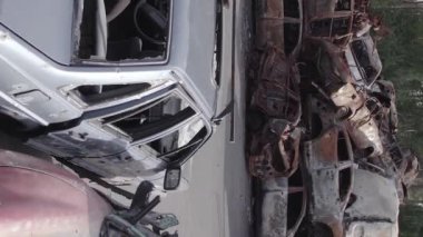 This stock vertical video shows a dump of shot and burned cars in Irpin, Bucha district , grey, flat video