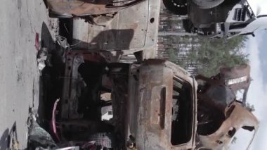 This stock vertical video shows a dump of shot and burned cars in Irpin, Bucha district , grey, flat video