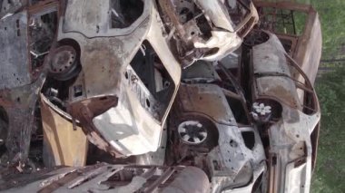 This stock vertical video shows a dump of shot and burned cars in Irpin, Bucha district , grey, flat video
