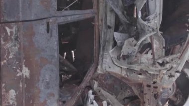 This stock vertical video shows a dump of shot and burned cars in Irpin, Bucha district , grey, flat video