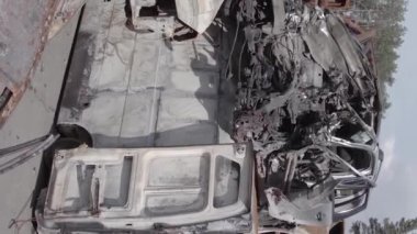 This stock vertical video shows a dump of shot and burned cars in Irpin, Bucha district , grey, flat video