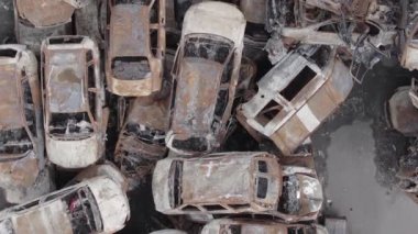 This stock vertical video shows a dump of shot and burned cars in Irpin, Bucha district , grey, flat video