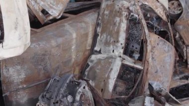 This stock vertical video shows a dump of shot and burned cars in Irpin, Bucha district , grey, flat video