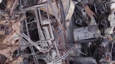 This stock vertical video shows a dump of shot and burned cars in Irpin, Bucha district , grey, flat video