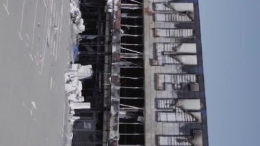 This stock vertical video shows a destroyed building of a shopping center in Bucha during the war in Ukraine, grey, flat video