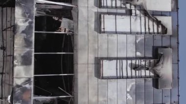 This stock vertical video shows a destroyed building of a shopping center in Bucha during the war in Ukraine, grey, flat video