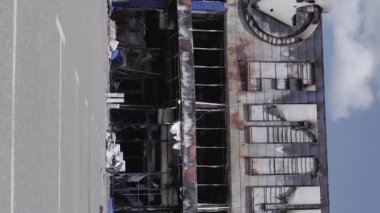 This stock vertical video shows a destroyed building of a shopping center in Bucha during the war in Ukraine, grey, flat video